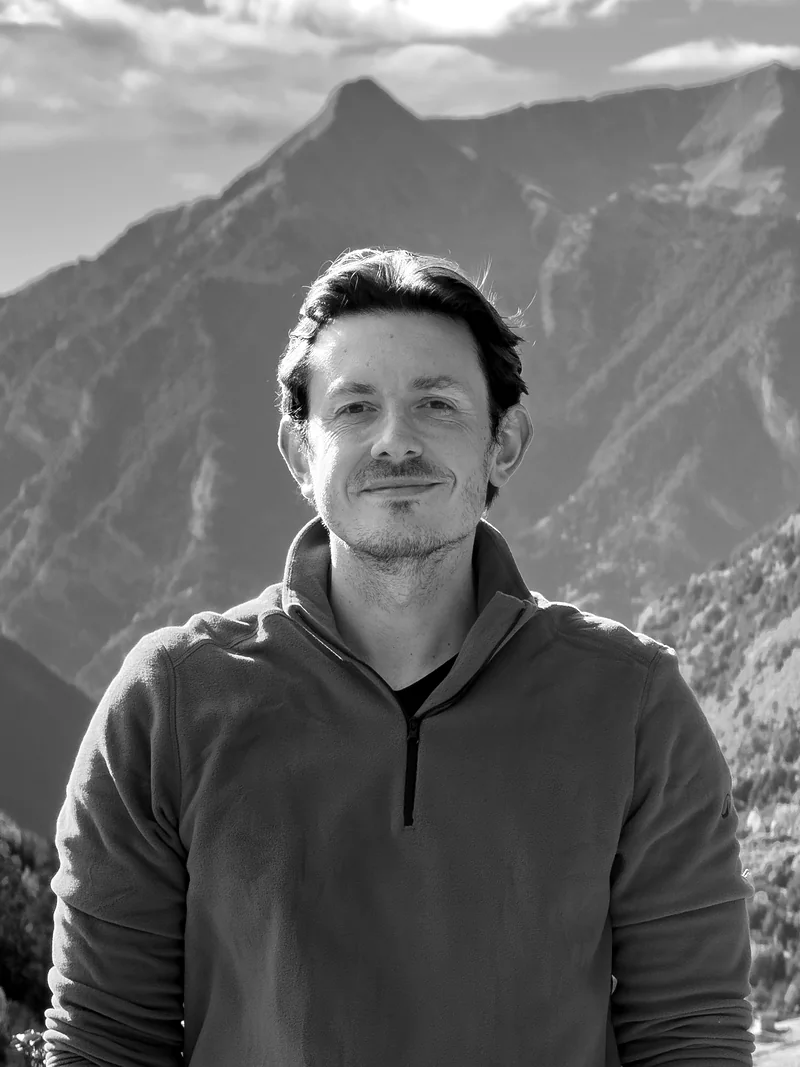 Dan Griffiths standing in front of mountains, in black and white