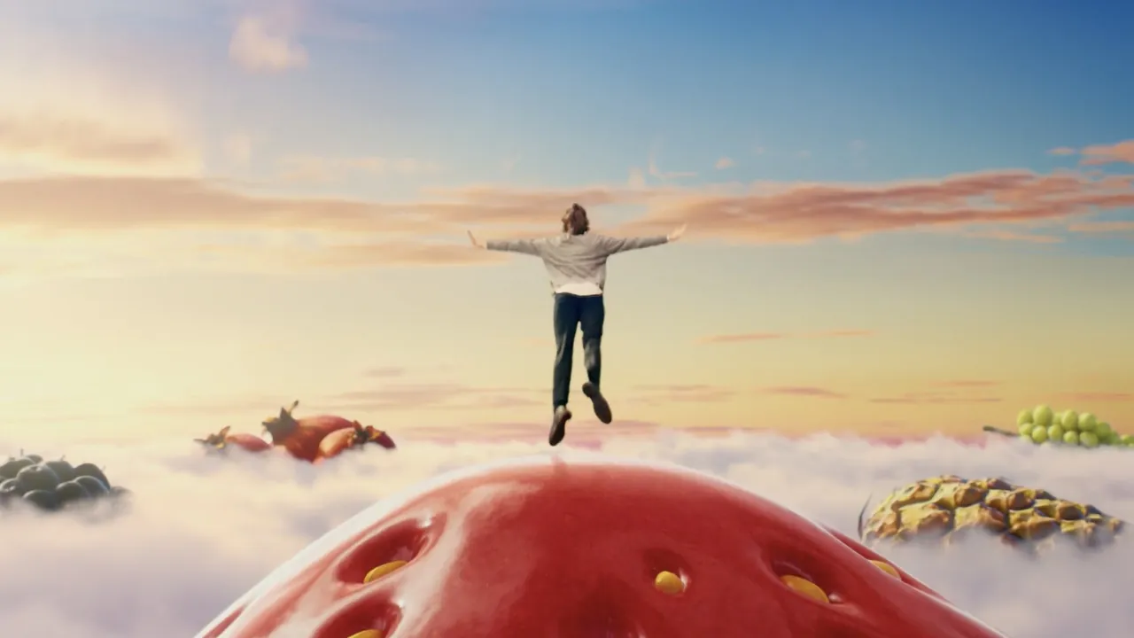 A man standing arms out on top of a giant strawberry
